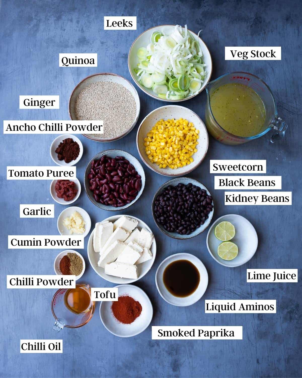 Ingredients for tofu quinoa bowl laid out on a dark blue surface.