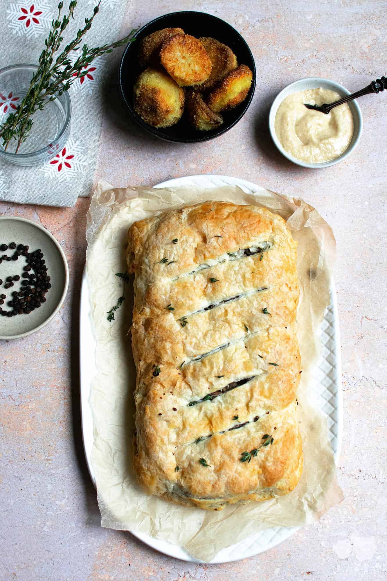 Mushroom wellington on a platter with pinch bowls around the edge