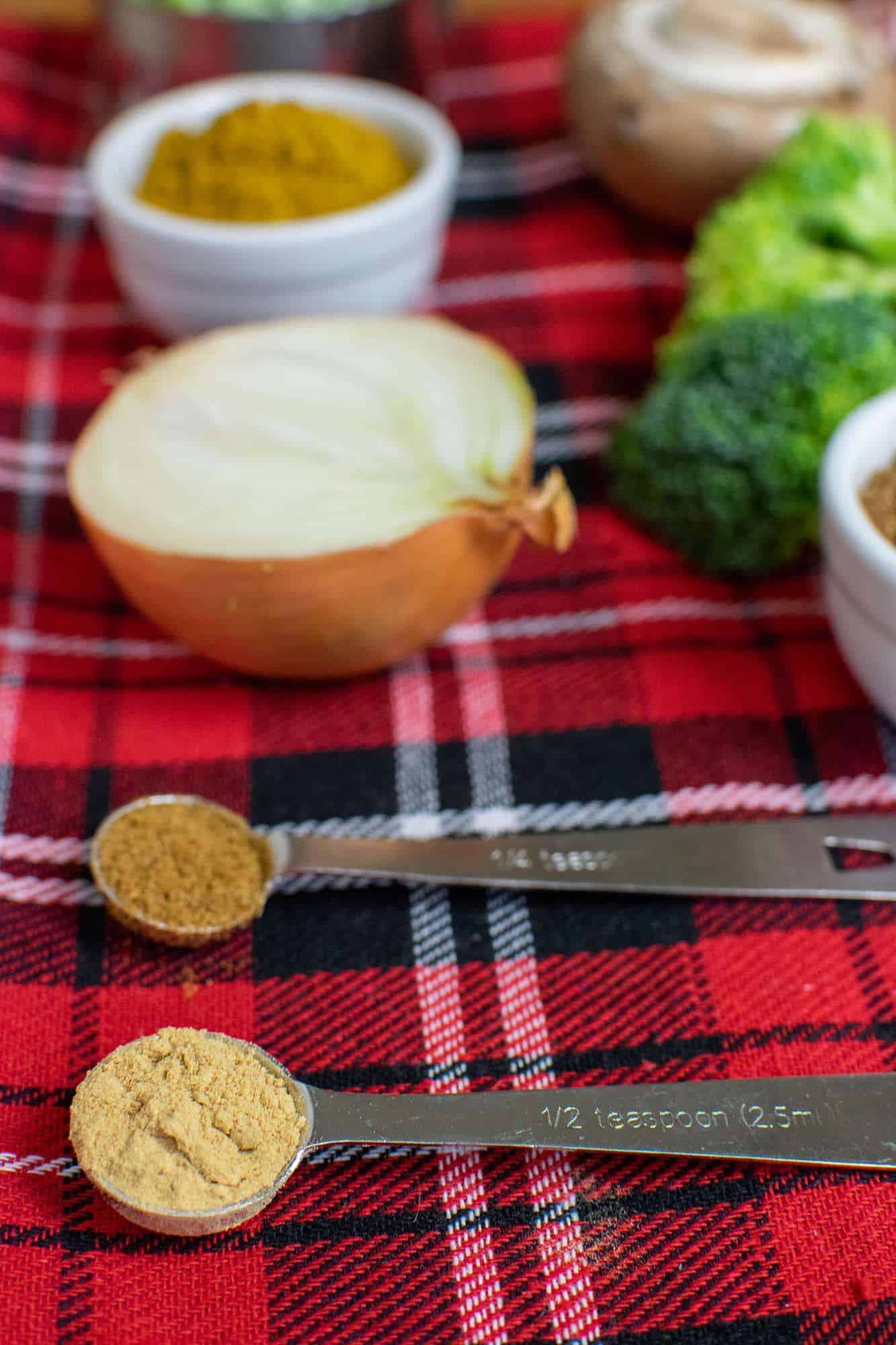 Close up of ginger powder and Chinese five spice in two separate measuring spoons