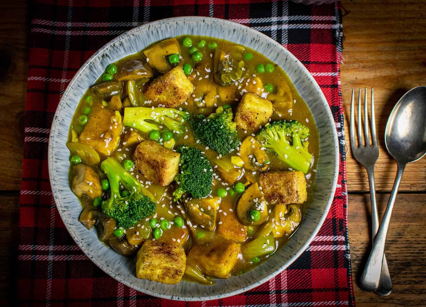 Landscape photos of the curry in a wide bowl with a fork and spoon next to it.