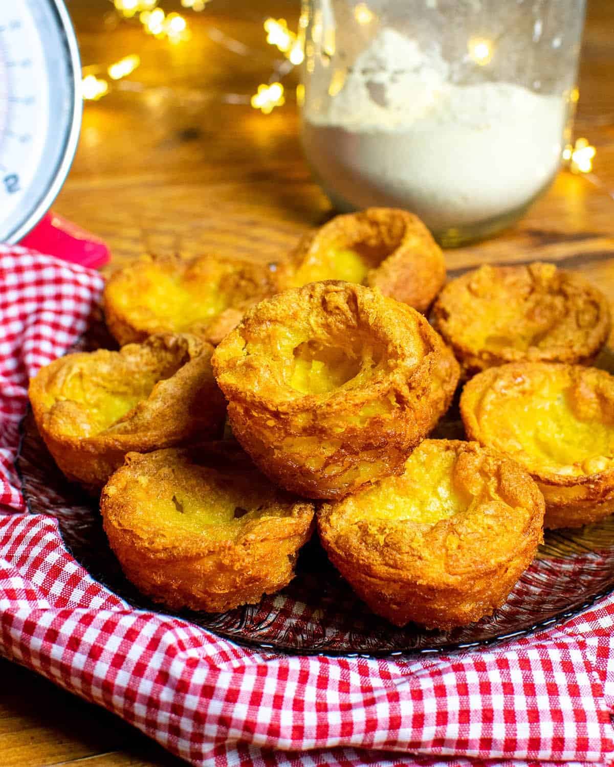 Vegan Yorkshire Puddings on a glass plate with a red and white cloth around it.