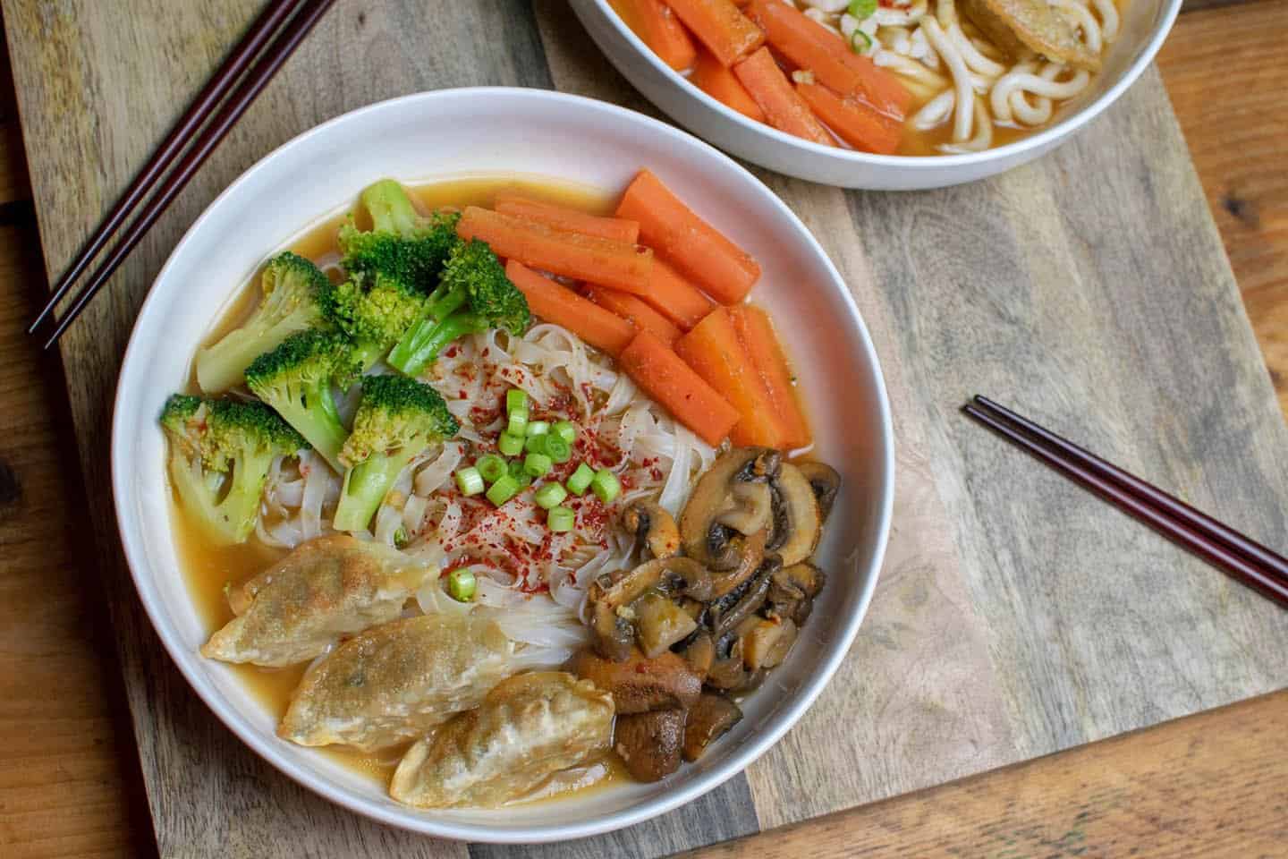 Vegan Ramyeon in a white bowl with mushrooms, broccoli and carrots and gyozas