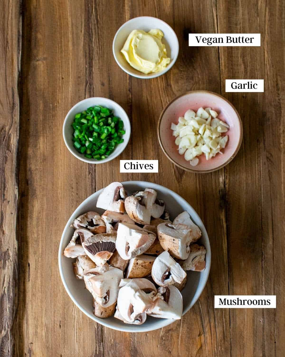 A table with ingredients in a bowl, showing mushrooms, chives, garlic and butter