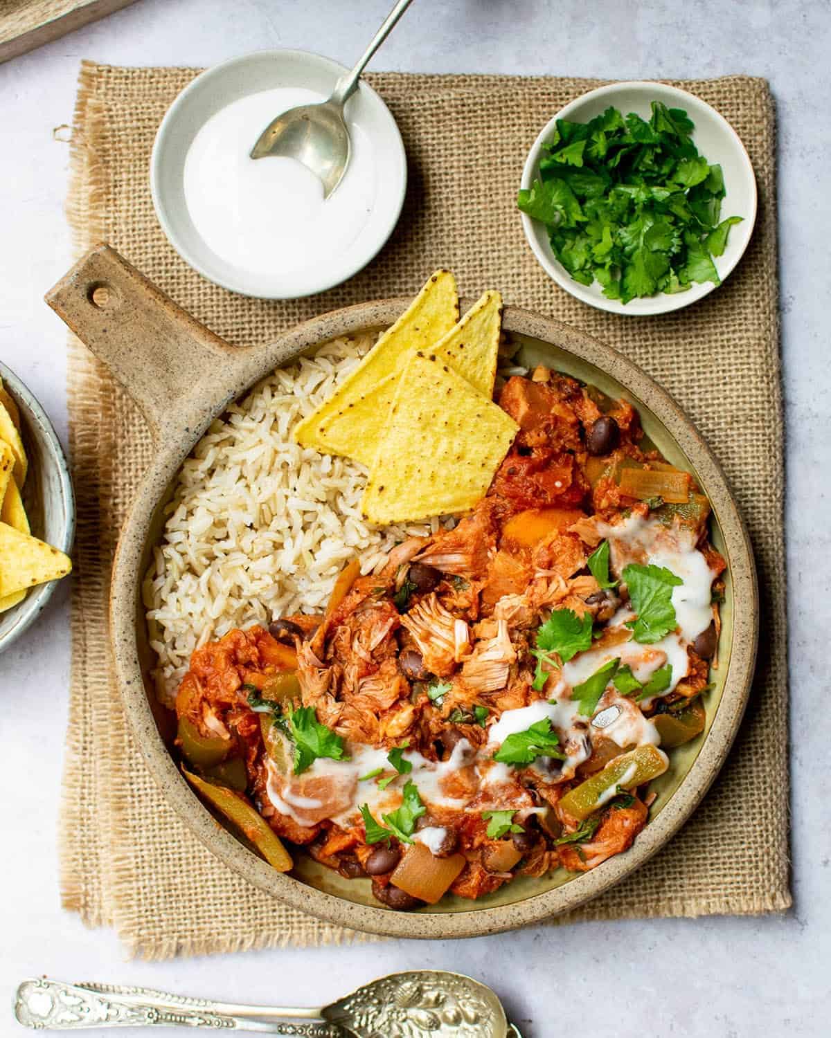 Top down view of jackfruit chilli with rice and condiments