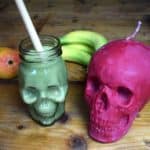 Matcha smoothie in a skull glass next to a skull candle