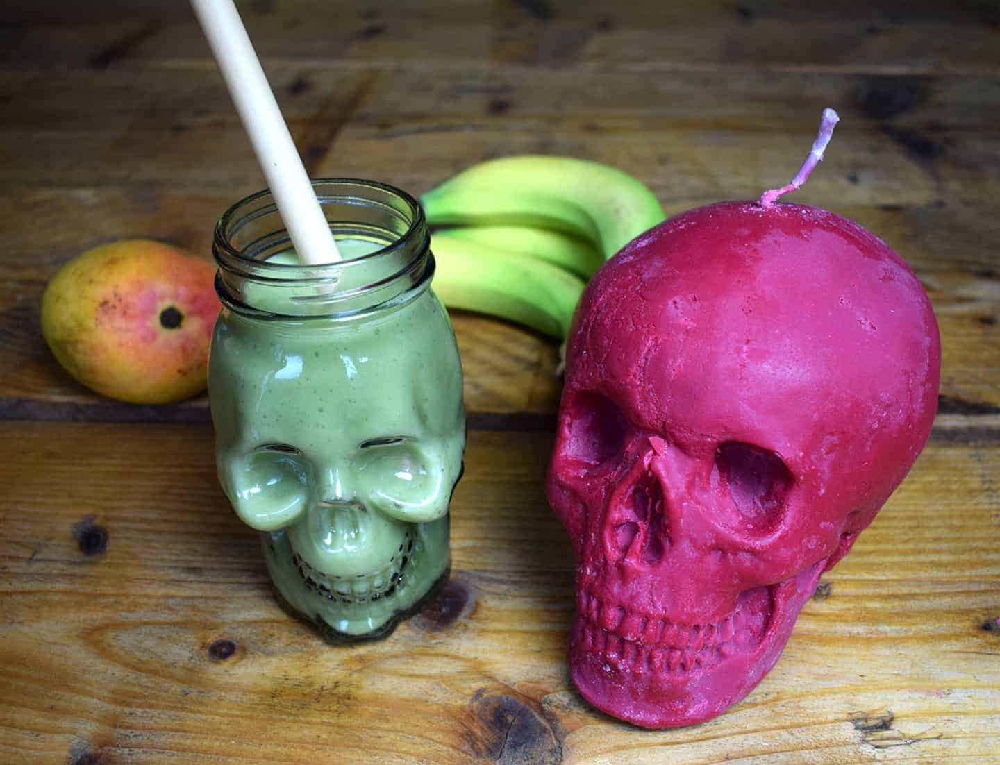 Matcha smoothie in a skull glass next to a skull candle