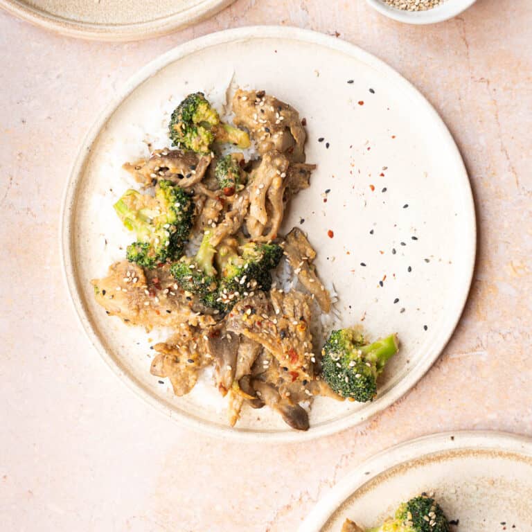 Oyster mushroom stir fry on a plate with rice and broccoli.