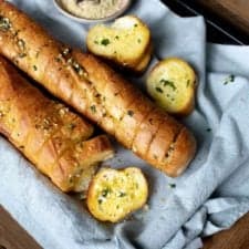 Top down view of two vegan garlic bread baguettes with one slice facing upwards
