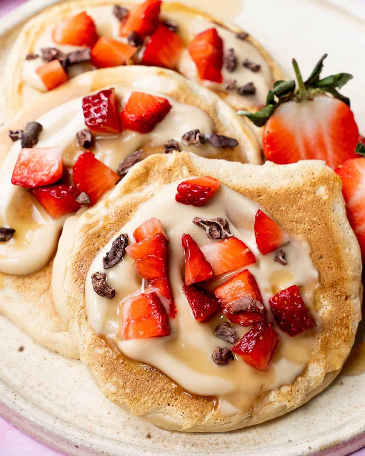 Vegan pancakes with strawberries, yoghurt and cacao nibs.