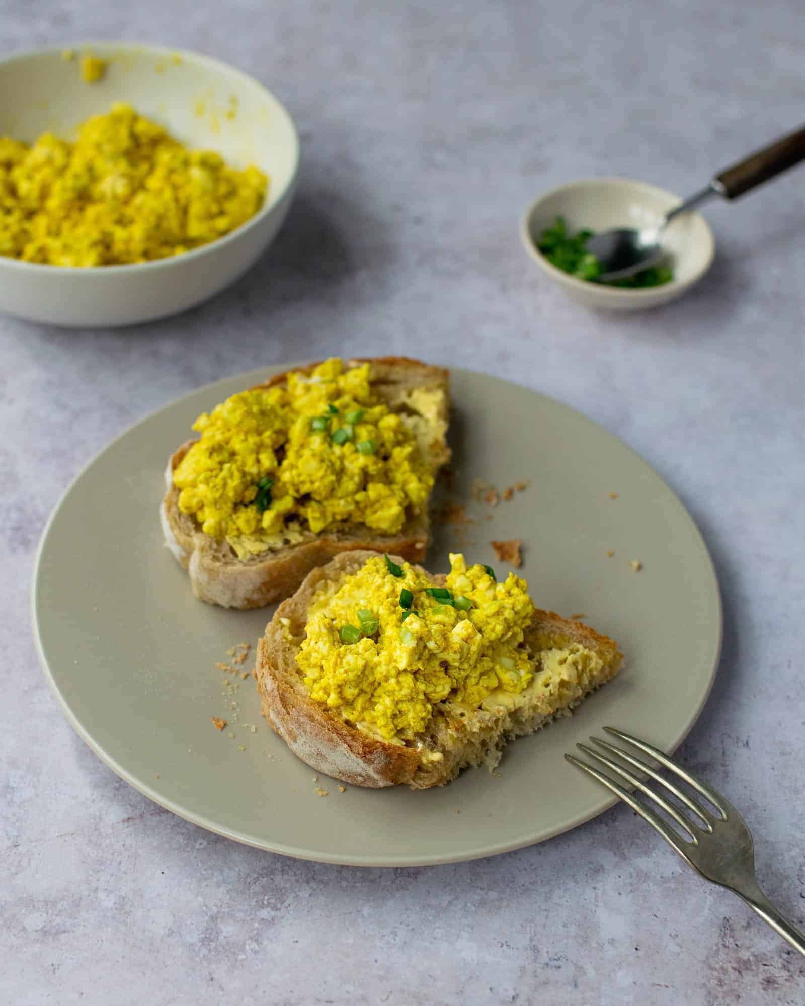 Two halves of sourdough toast with silken tofu scramble on it