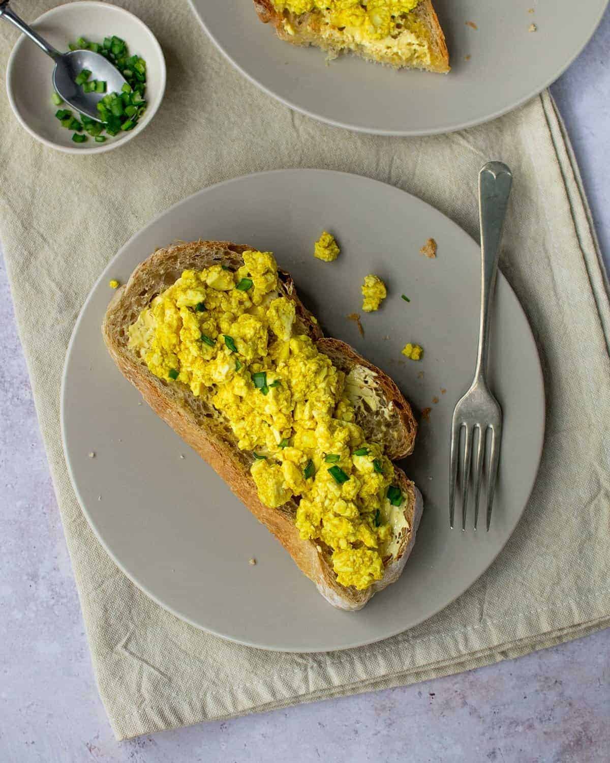 Top down view of scrambled tofu on a slice of sourdough with a fork on the plate