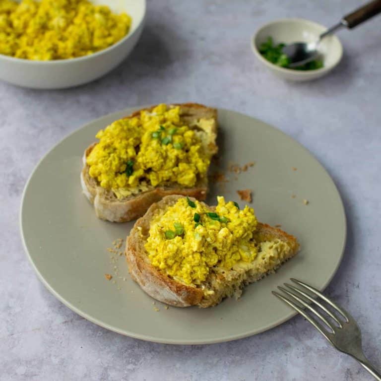 Soft tofu scramble on two halves of toast on a p;ate