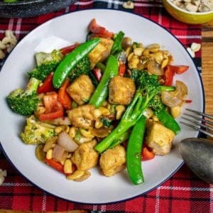 Thai Cashew Stir-fry on a white plate with cutlery balanced on it.