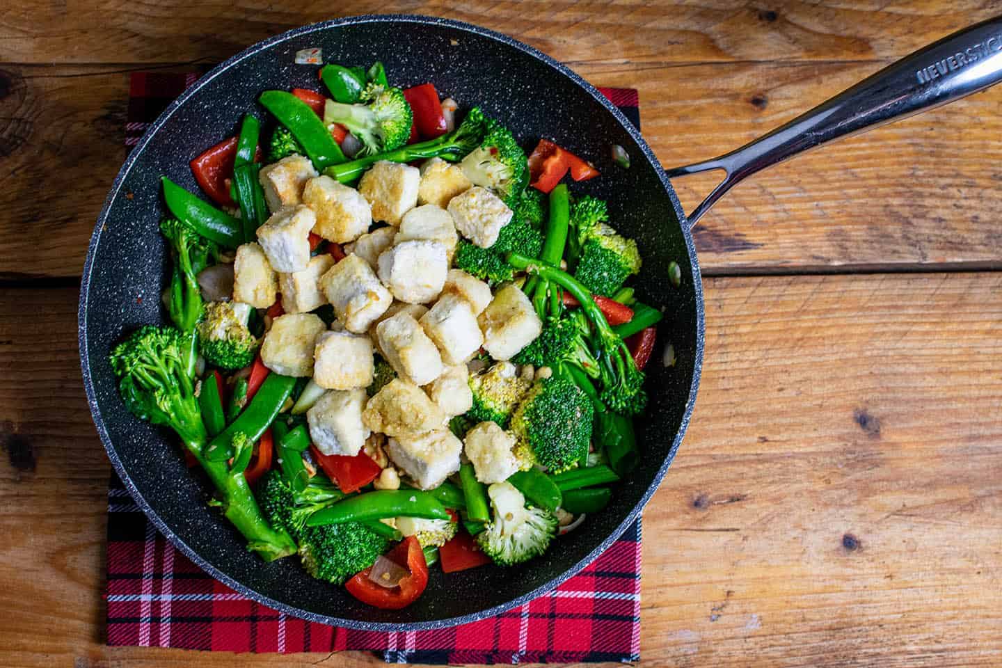 Wok with vegetables and tofu in it.