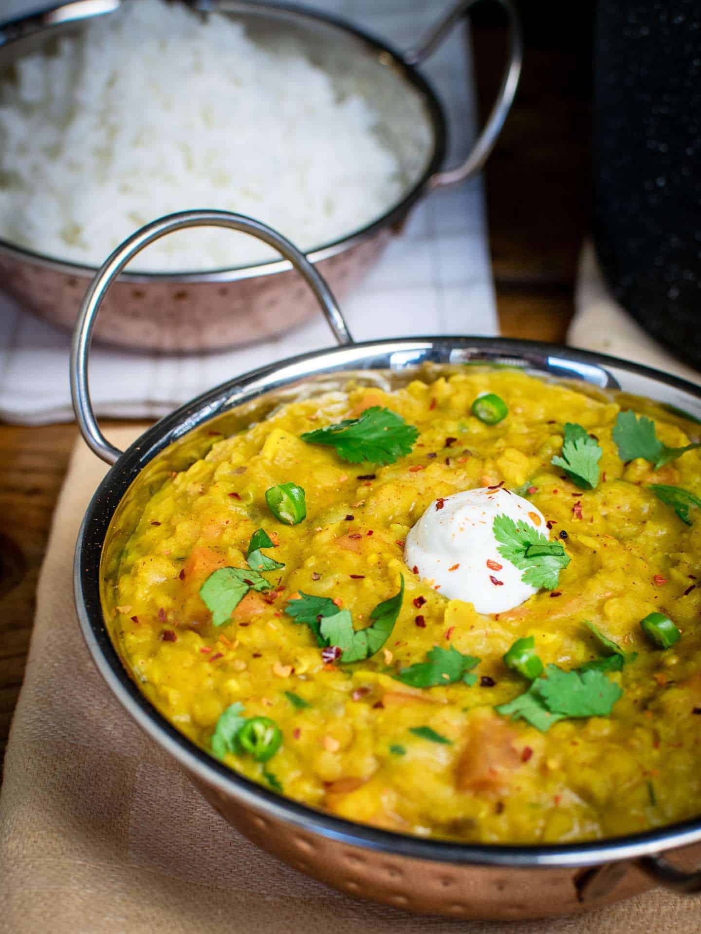 Vegan dahl close up, it's yellow and full to the top in a metalic Indian dish.