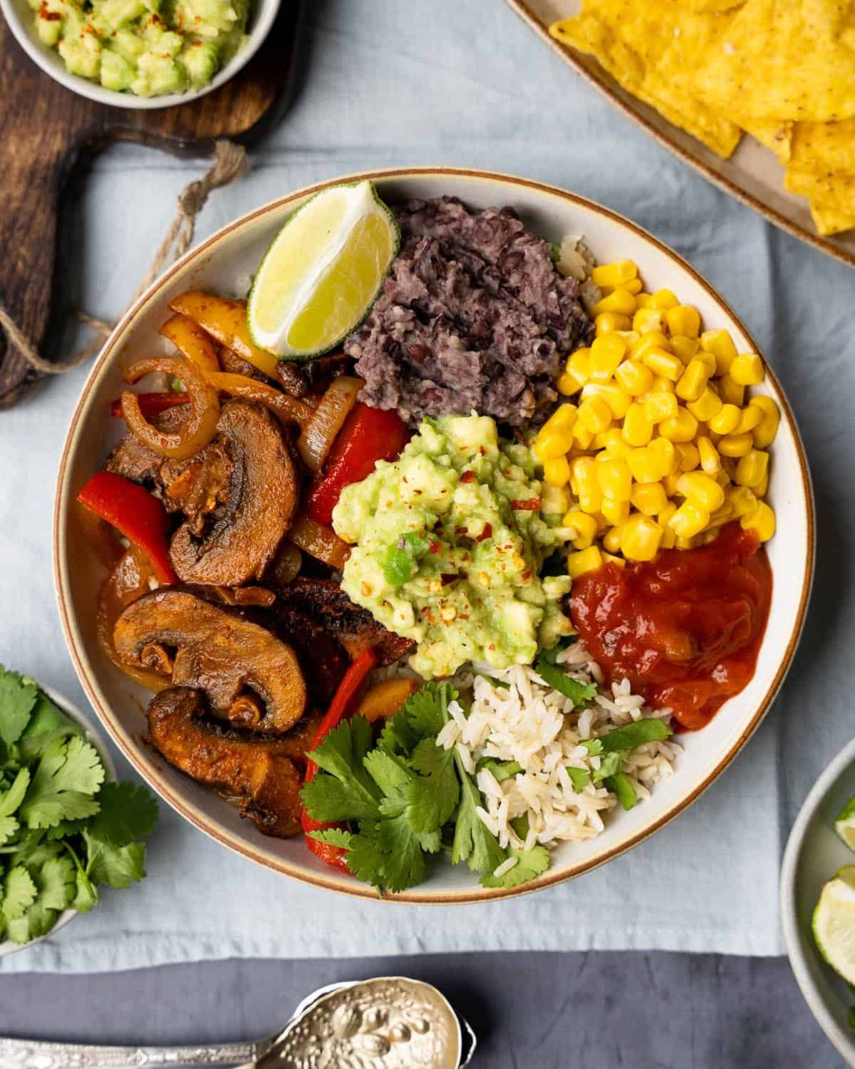 Mexican Buddha bowl served with a lime wedge, avocado and tortilla chips.