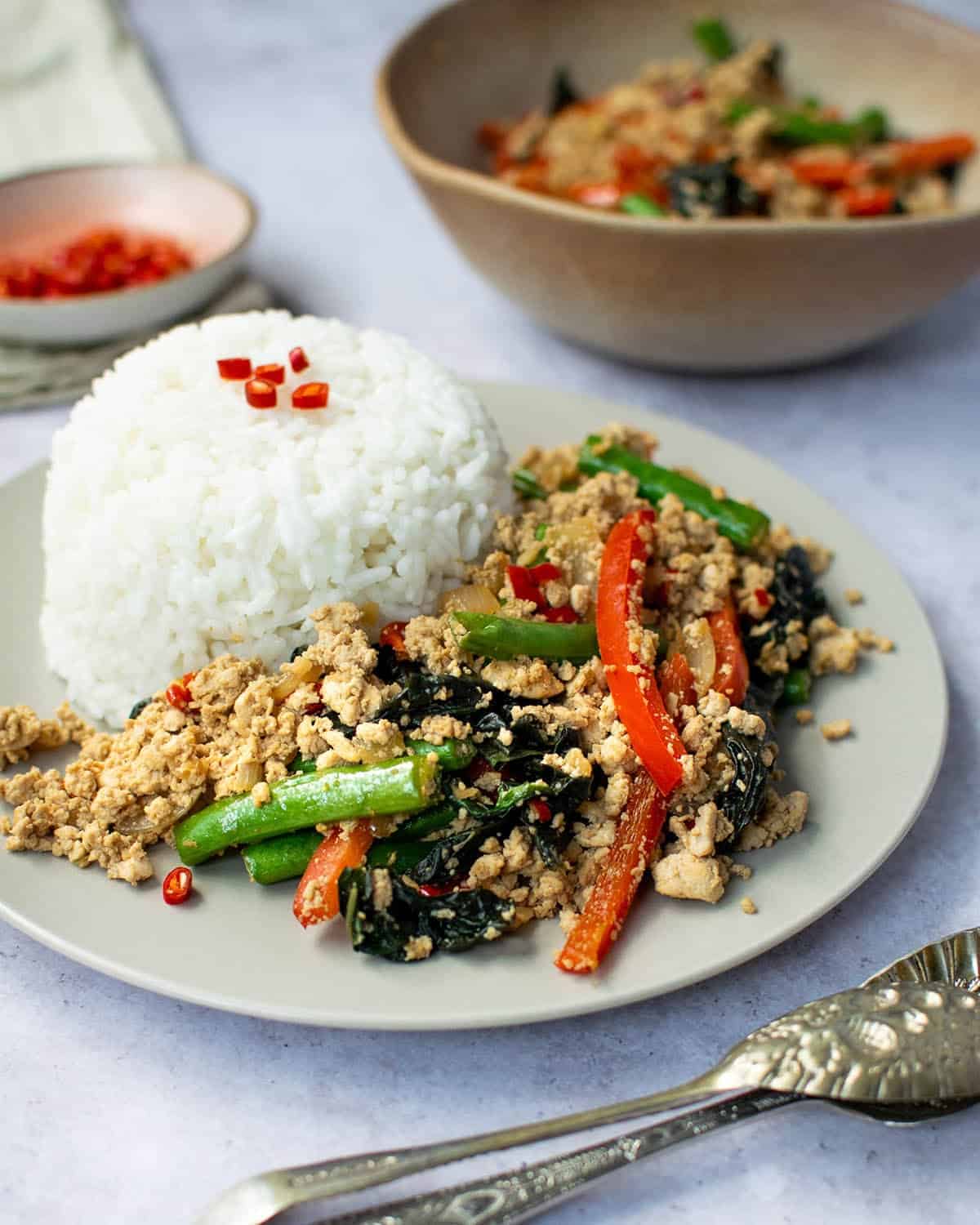 Thai basil tofu on a plate next to a mound of rice