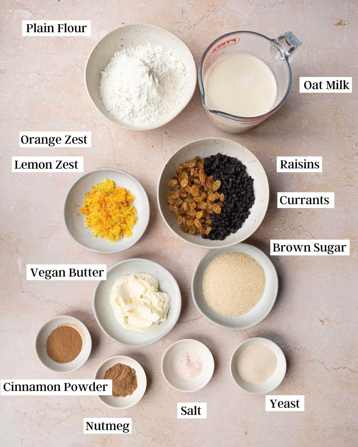 Ingredients for vegan hot cross buns laid out in bowls.