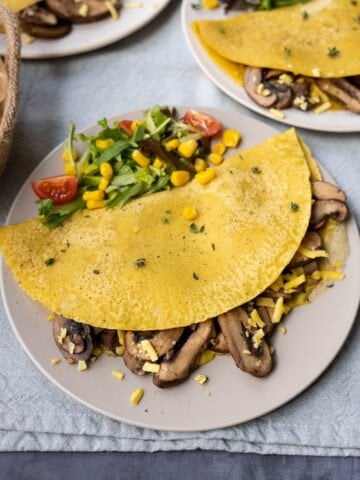 Chickpea flour omelette filled with mushrooms, with a side salad and bread.