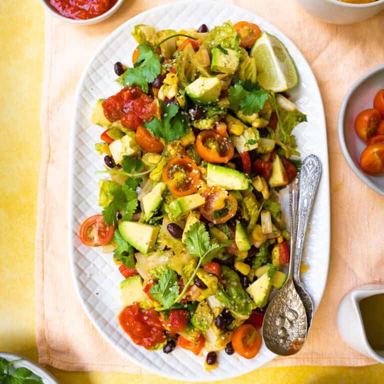 Vegan Mexican Salad on a large serving plate with ingredients around it.