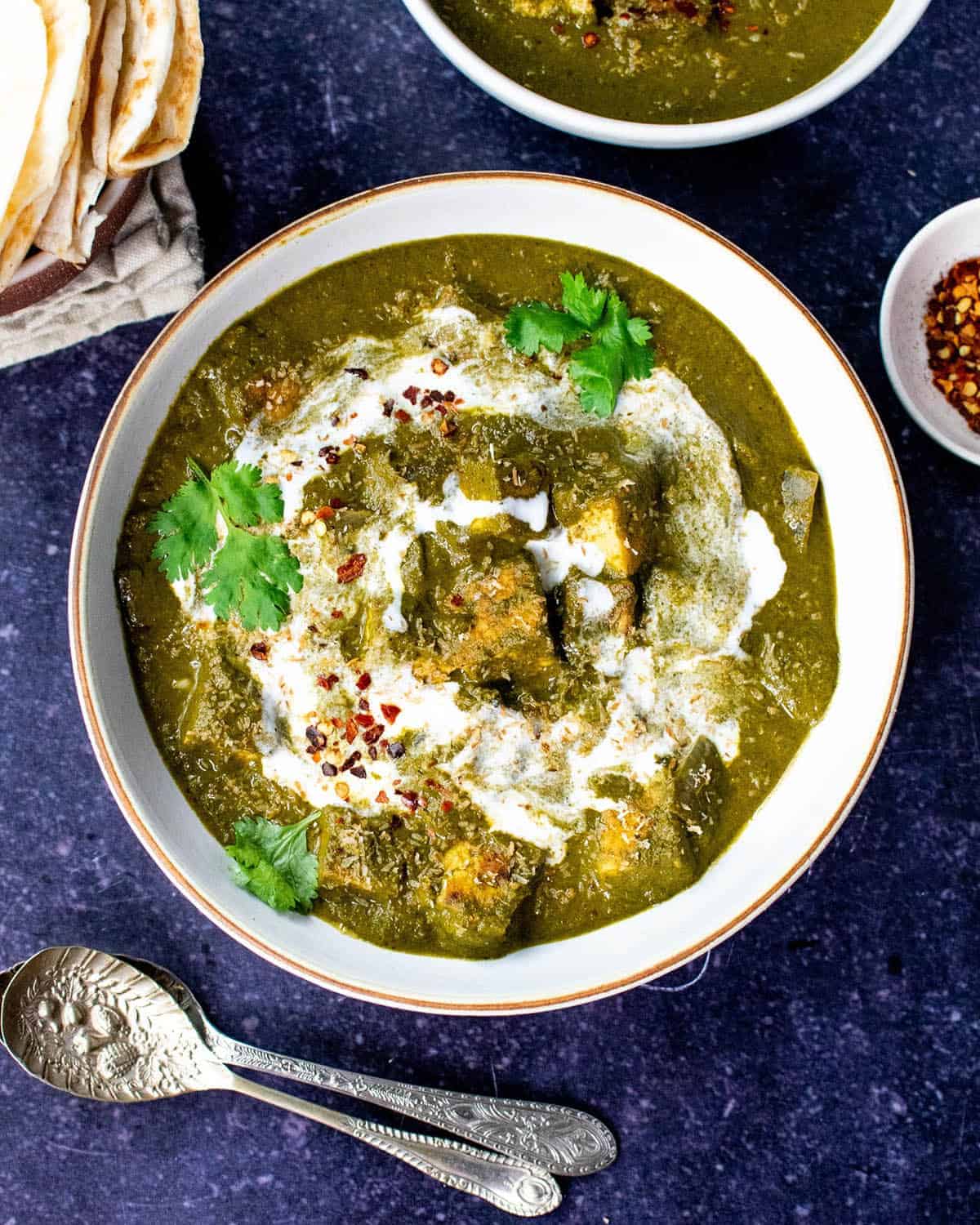 Vegan palak tofu topped with fresh coriander and coconut milk, served with chilli flakes.