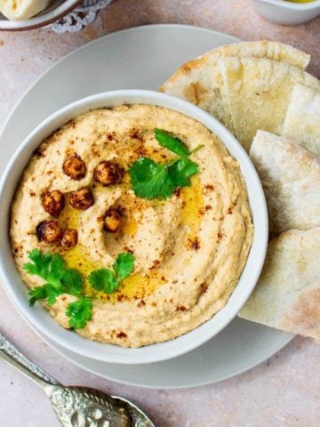Lebanese hummus in a bowl with pitta to the side