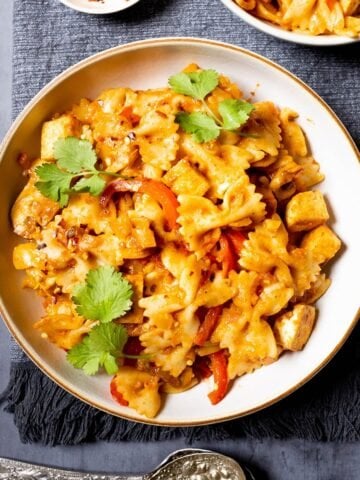 Tofu pasta in a bowl with peppers, herbs and chilli flakes.