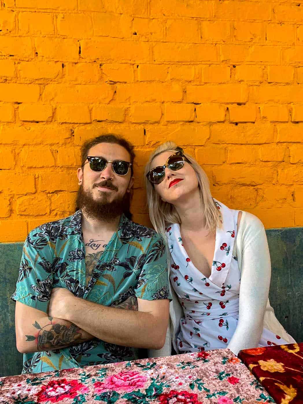 Vegan Punks – Jess and dan in Kiev, sitting with backs to an orang and blue wall