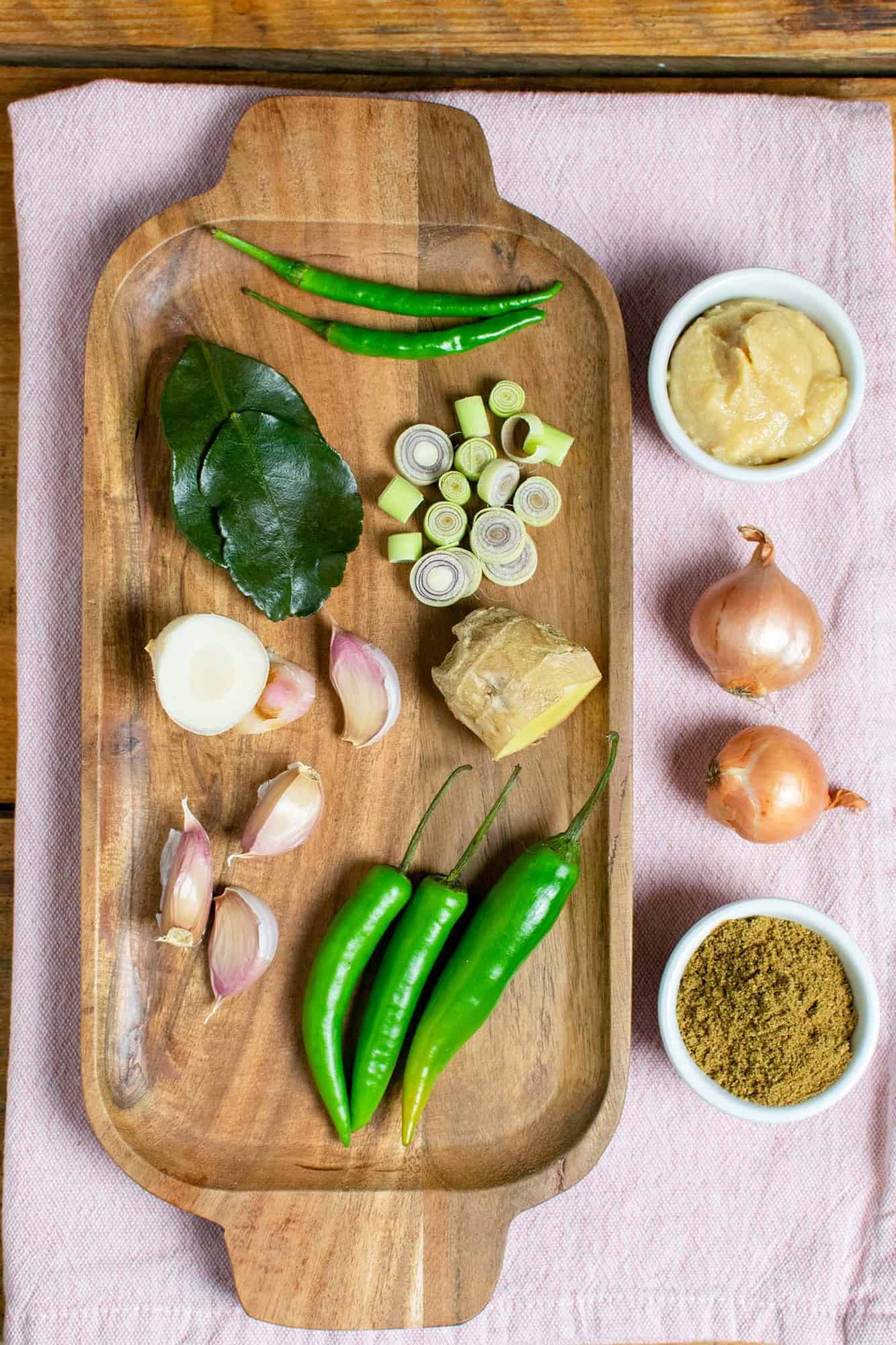 Ingredients for Thai green curry paste set out on a wooden tray