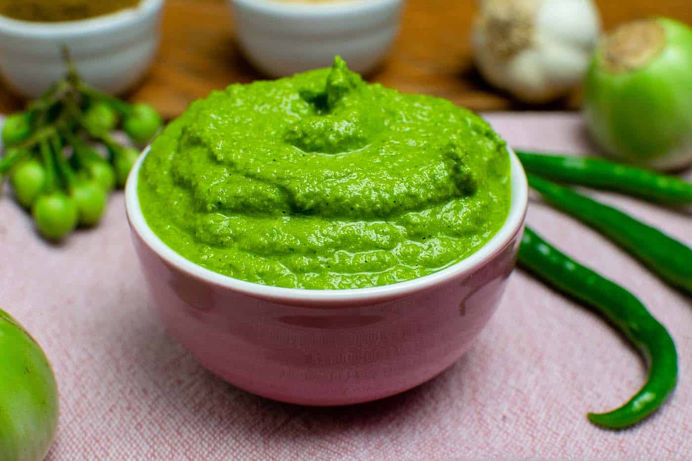 Vegan Thai green curry paste in a pink bowl with chillies Thai egglants in the background