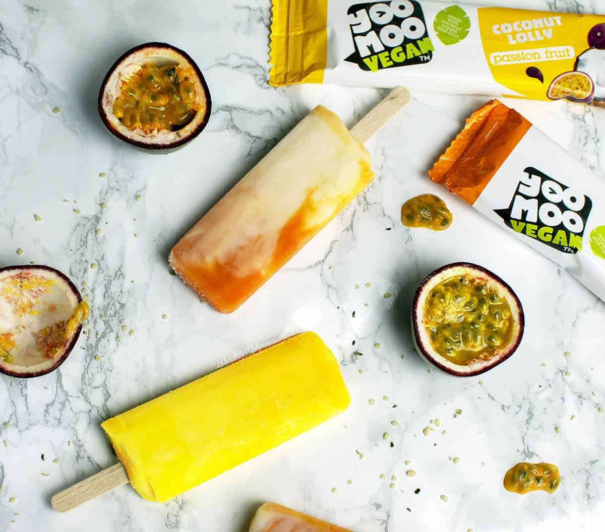 Yoomoo vegan lollies on a whiet background with passion fruits decorating the background 