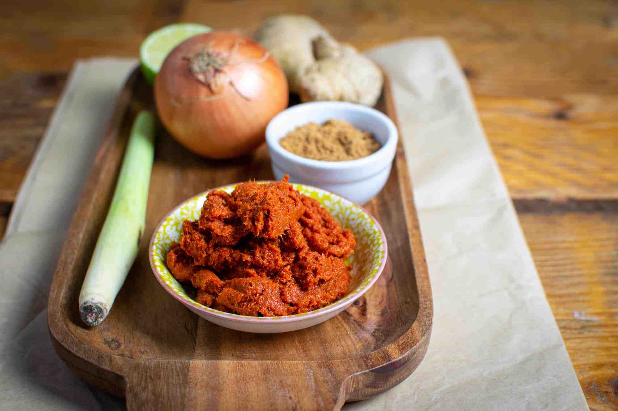 Thai red curry paste on a tray with sugar, onion, lemongrass, ginger and lime