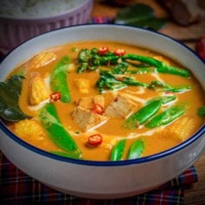 Thai red vegetable curry in bowl with rice in the background