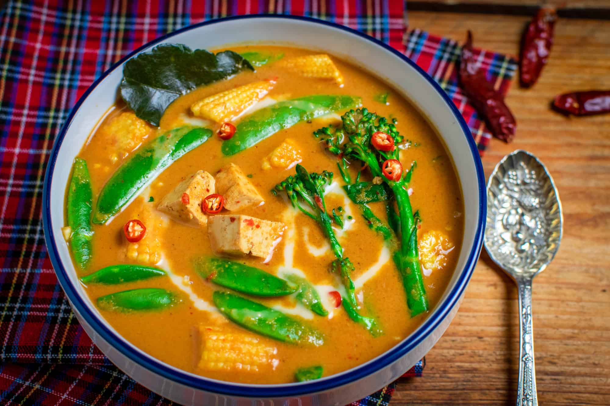 Thai red vegetable curry with tofu in a bowl with a spoon next to it