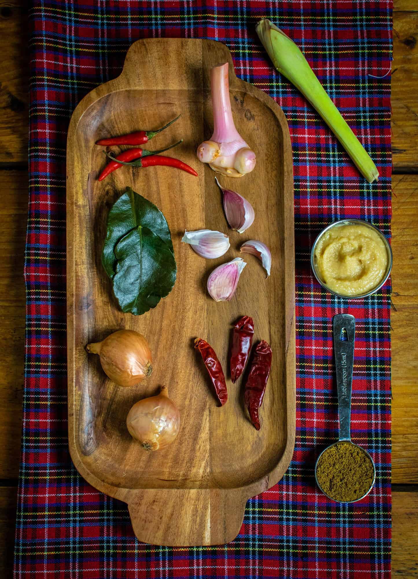 Ingredients for vegan Thai red curry paste including garlic, shallots, mis paste, cumin powder, kaffir lime leaves, galangal and dried chillies