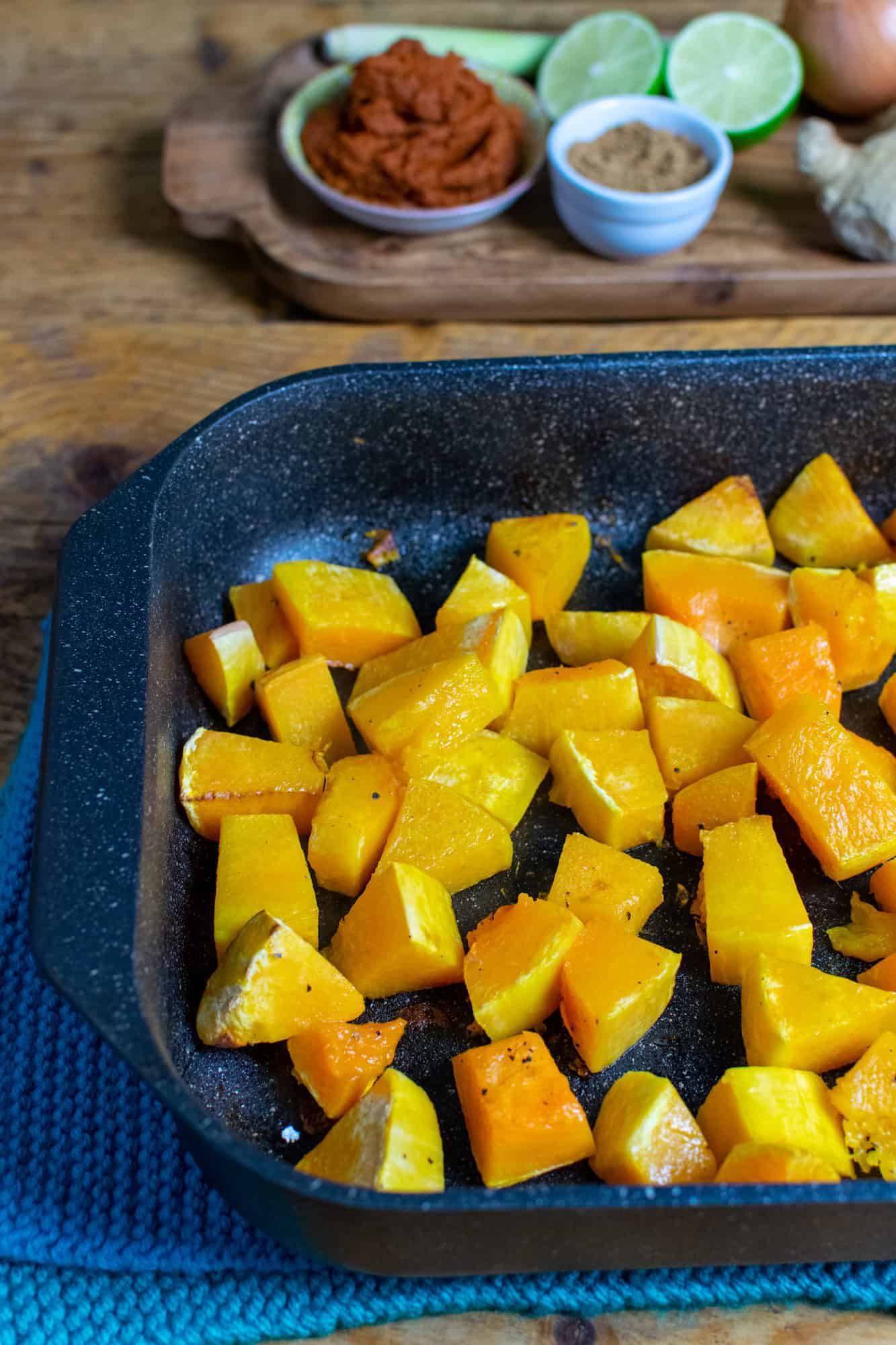 Chopped fresh pumpkin in a black speckled baking tray