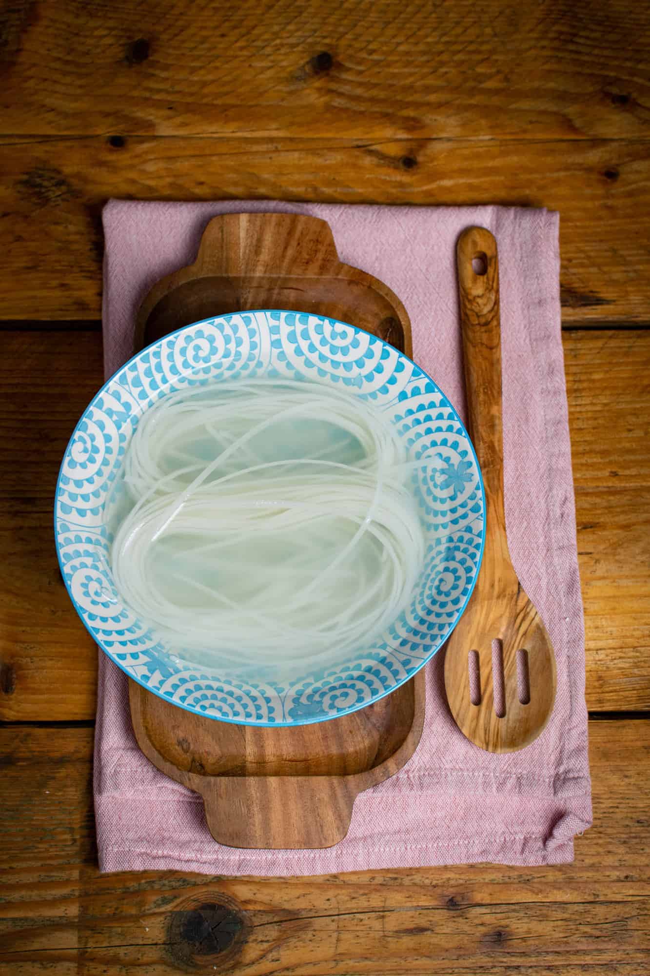 Rice noodles soaking in a blue bowl