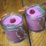 Peanut butter smoothie with berries in a clip jar topped with chia seed and a raspberry