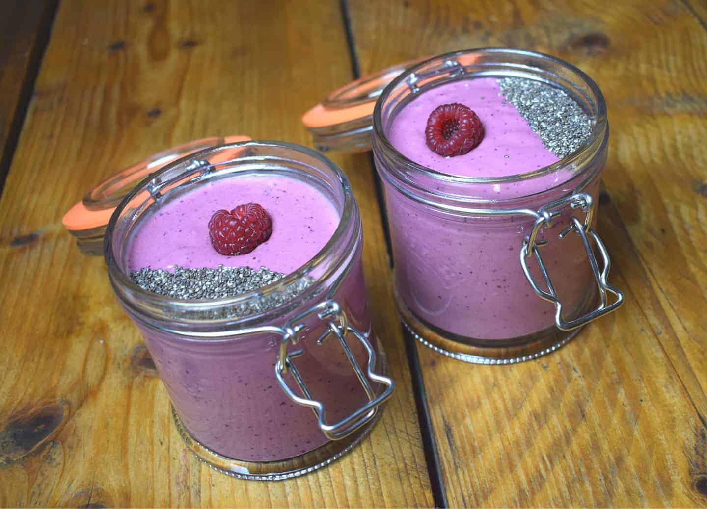 Peanut butter smoothie with berries in a clip jar topped with chia seed and a raspberry