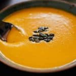 Spiced carrot and lentil soup in a bowl with black bean topping