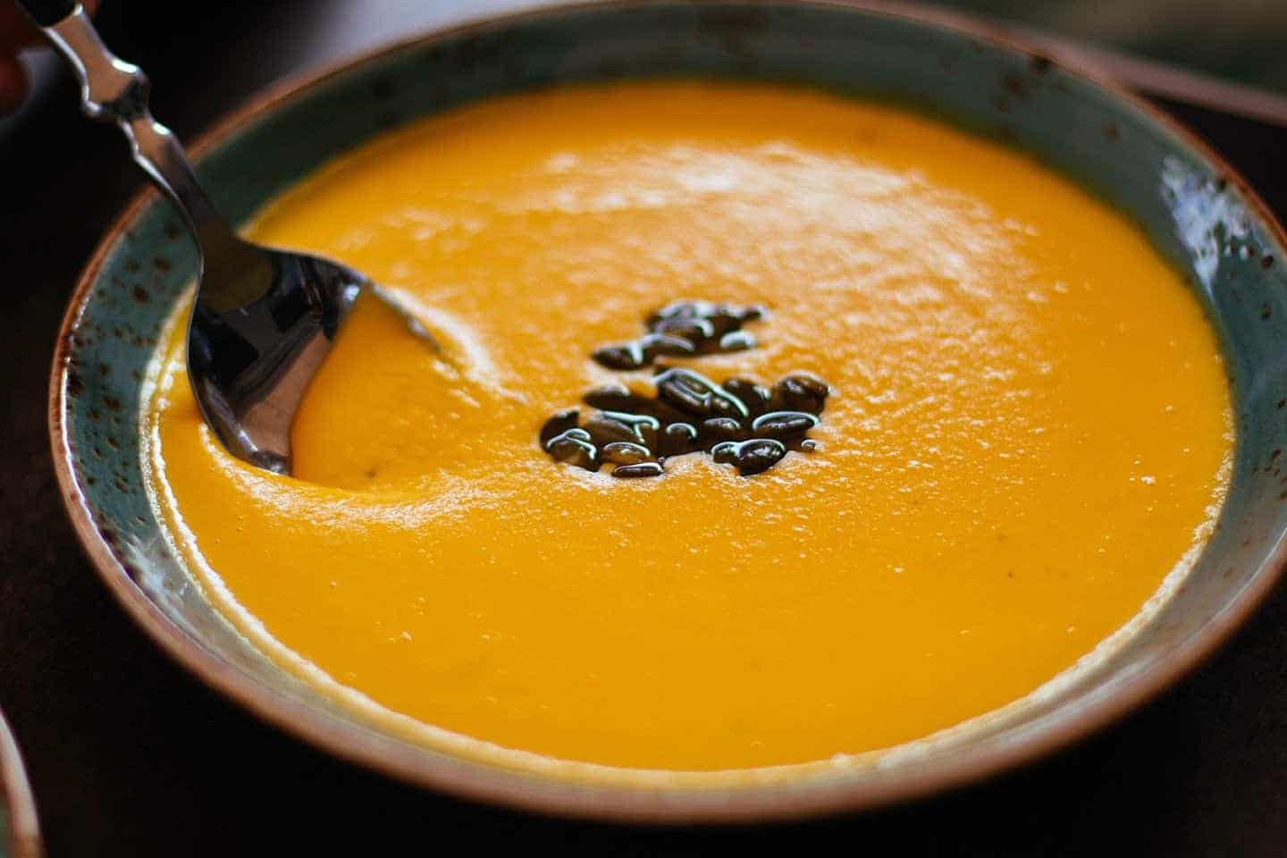 Spiced carrot and lentil soup in a bowl with black bean topping