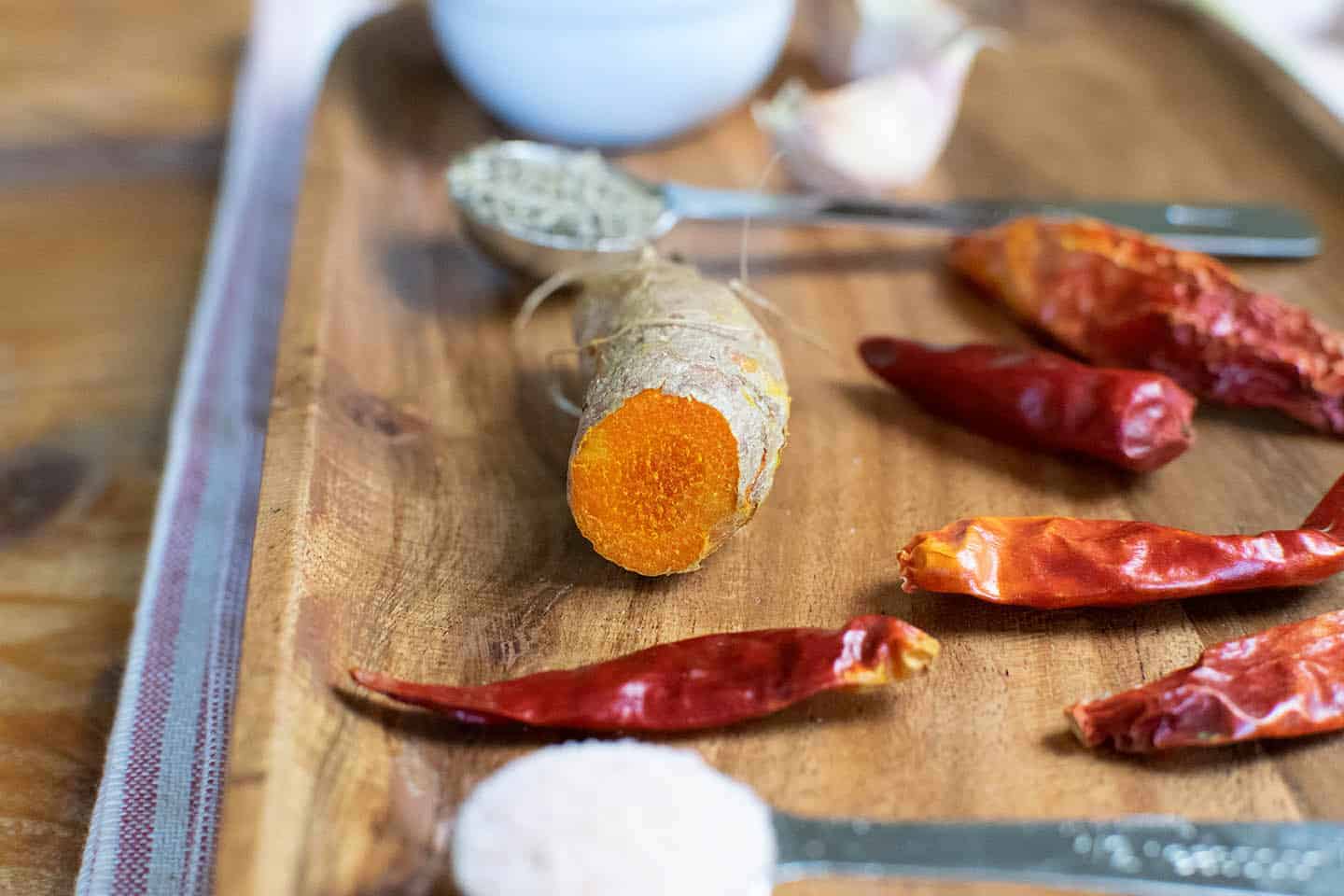 A picture of fresh turmeric with dried red chillies and other ingredients around it.