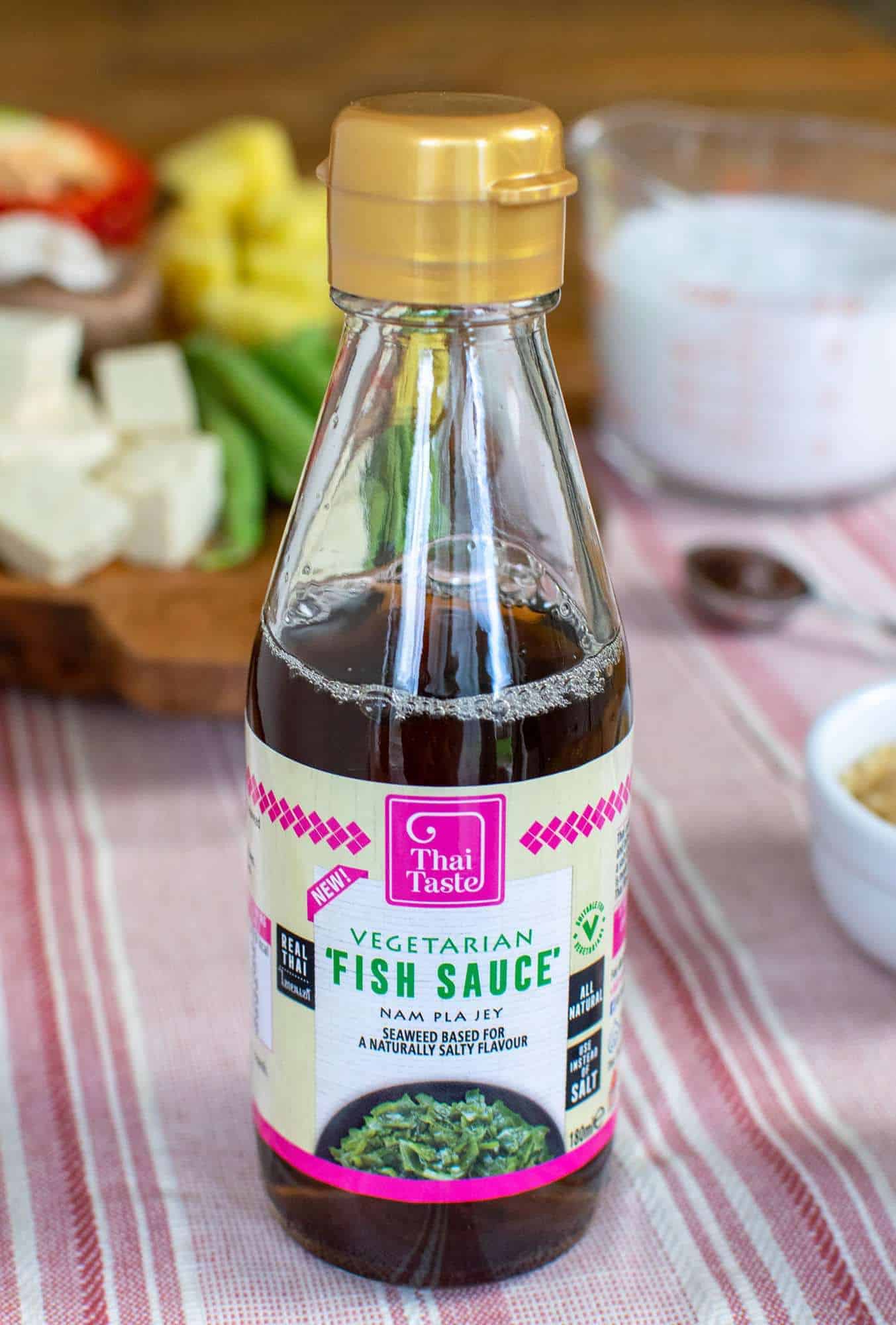 A bottle of vegan fish sauce in front of a tray full of ingredients.