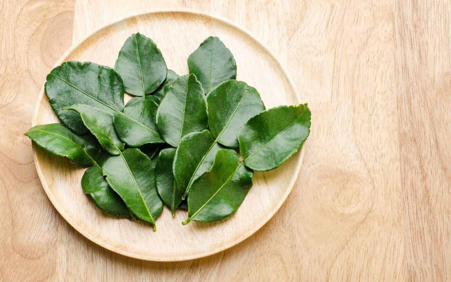 A wooden plate with kaffir lime leaves on it
