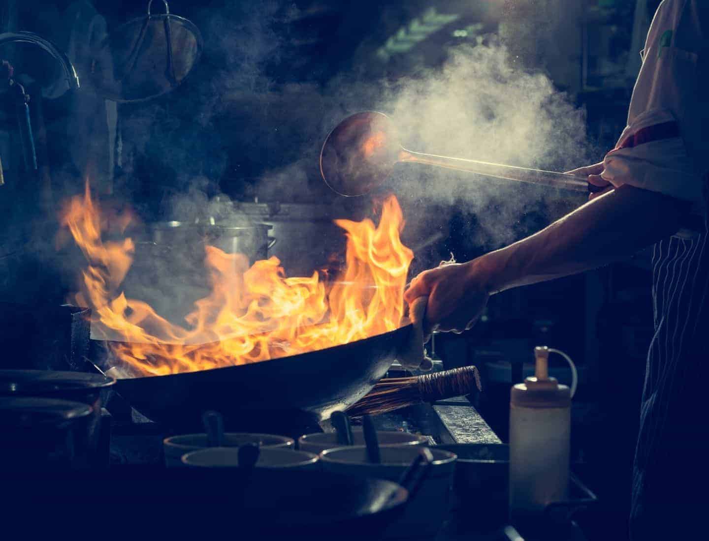 Man cooking with a wok that has been set on fire