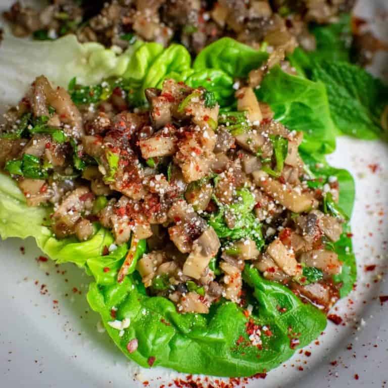 Square photo of mushroom larb on a leaf of baby gem sprinkled with chilli flakes