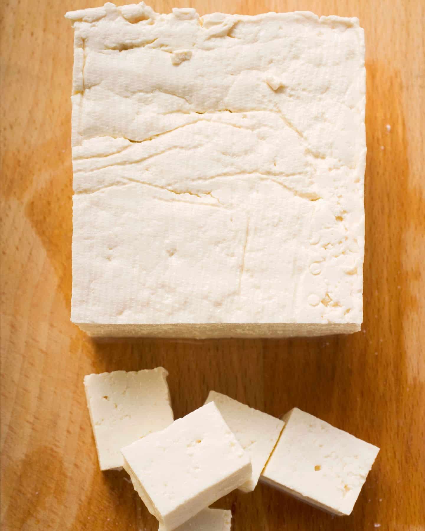 Block of firm tofu with some chunks chopped up