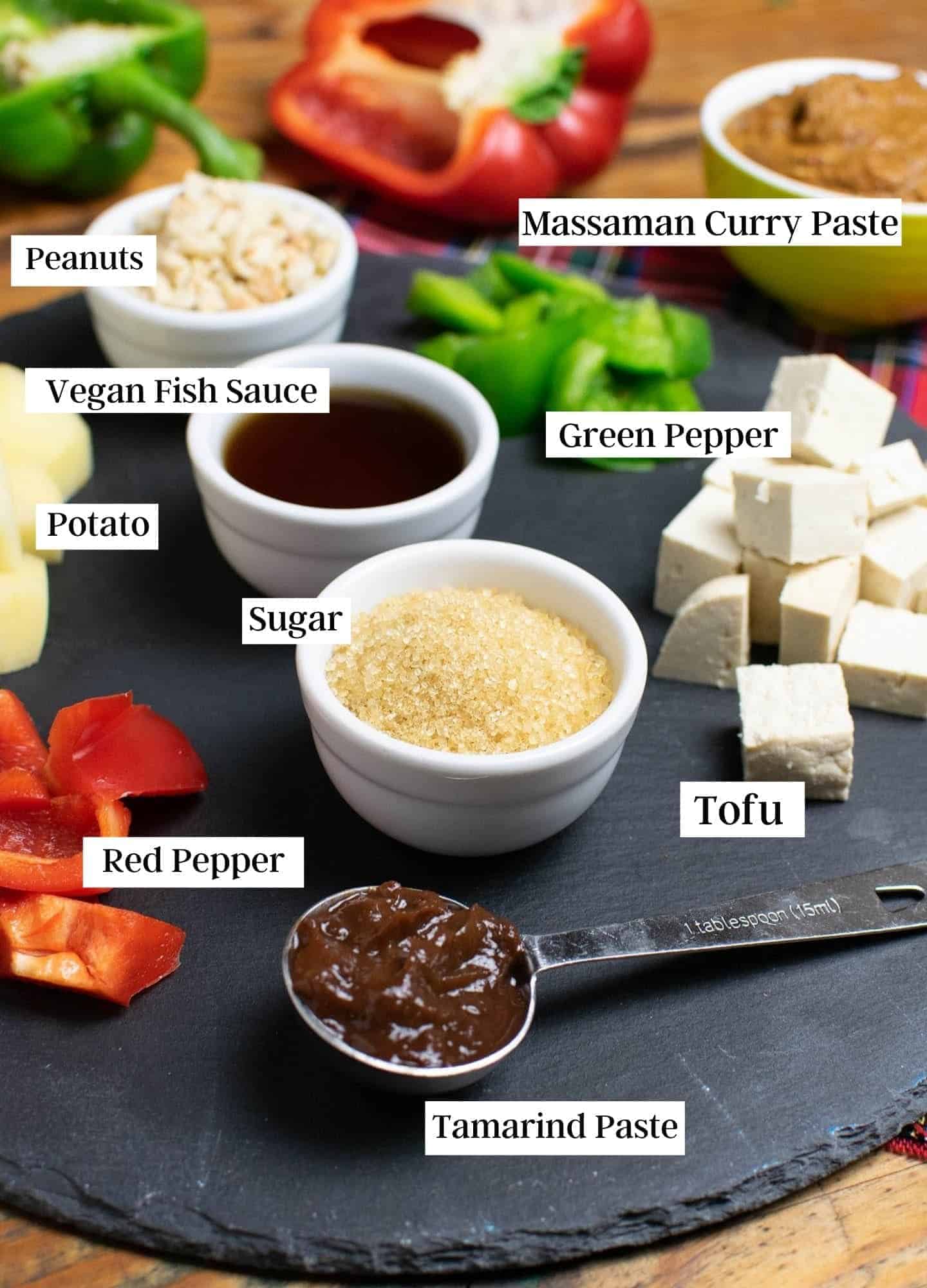 Ingredients on a circular slate showing lots of ingredients for this curry like fresh veg, tofu, sugar, vegan fish sauce and curry paste
