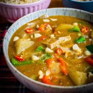 Vegetable Massaman Curry in a blue seckled bowl. Potatoes, tofu, chillies, peppers and peanuts are visible