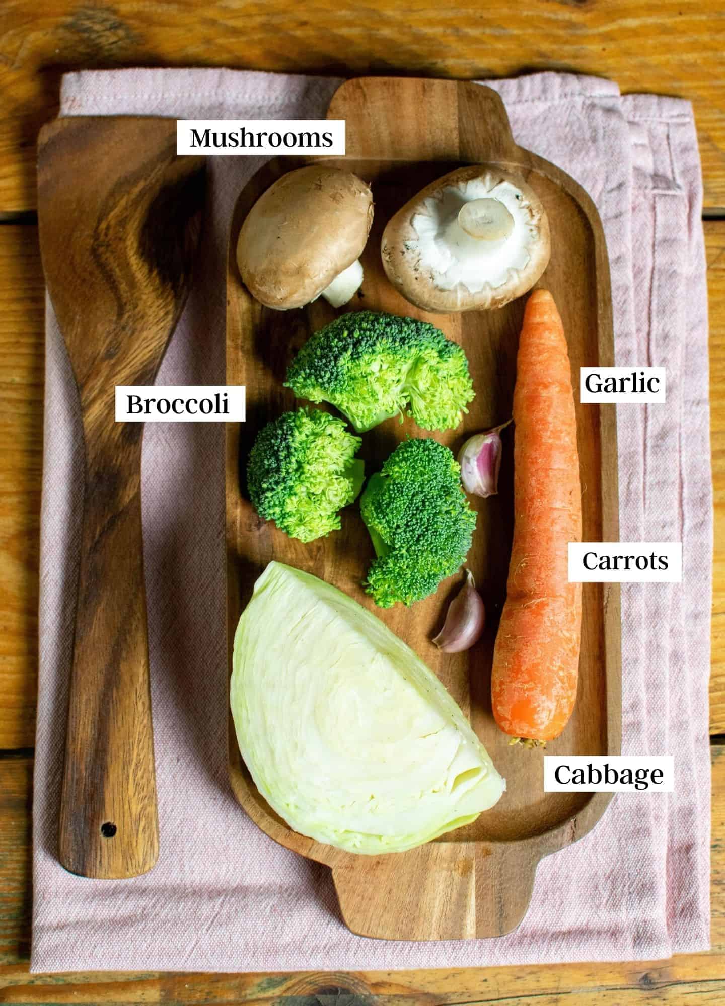 Mushrooms, carrots, cabbage, broccoli and garlic laid out on a chopping board